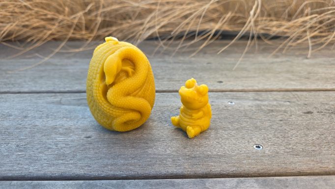 Gelbe Figur eines Eies mit einer Schlange und einer kleinen Bärenfigur daneben.