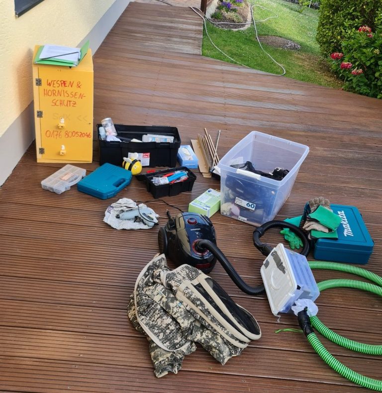 Ausrüstung zum Umsiedeln Werkzeuge und Materialien auf einem Holzboden, darunter Handschuhe und Behälter.